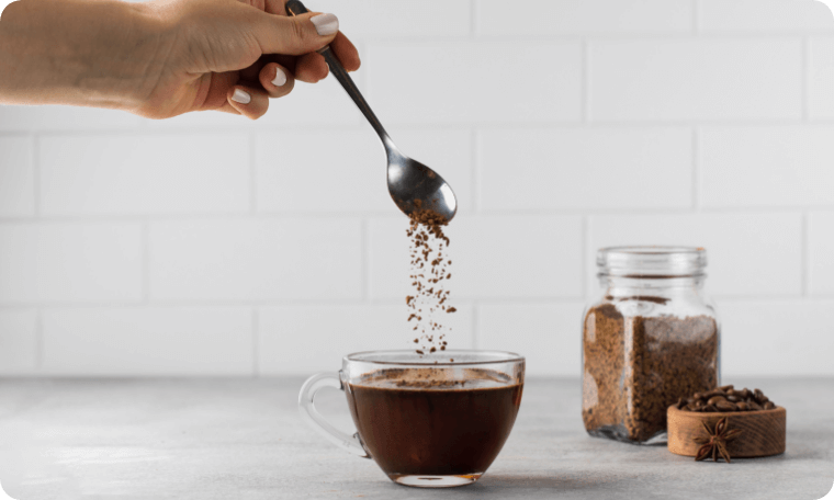 A Woman Adds Instant Coffee in Glass Mug