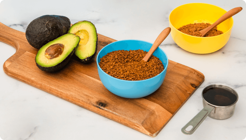 An Avocado and Waka Tea and Coffee on a Cutting Board Next to a Measuring Cup